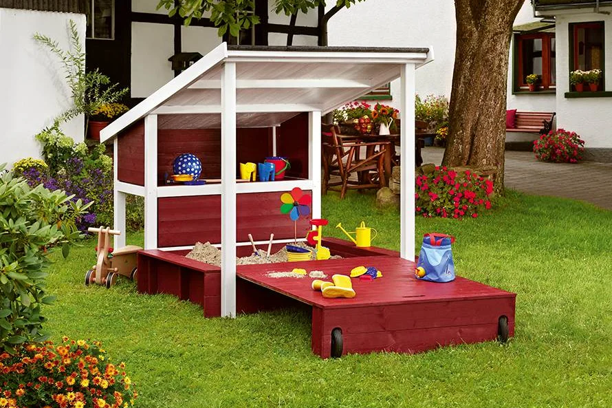 Ein roter und weißer Sandkasten mit Dach.